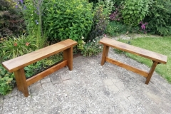A pair of rustic garden benches made from reclaimed scafold boards